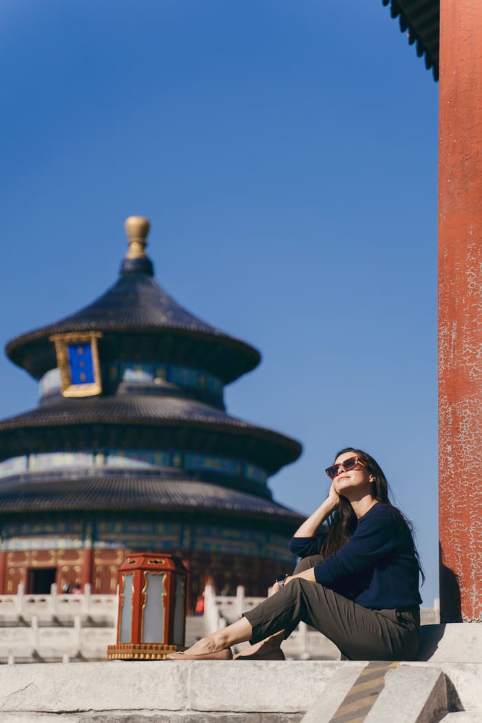 chica sentada con el palacio de beijin al fondo