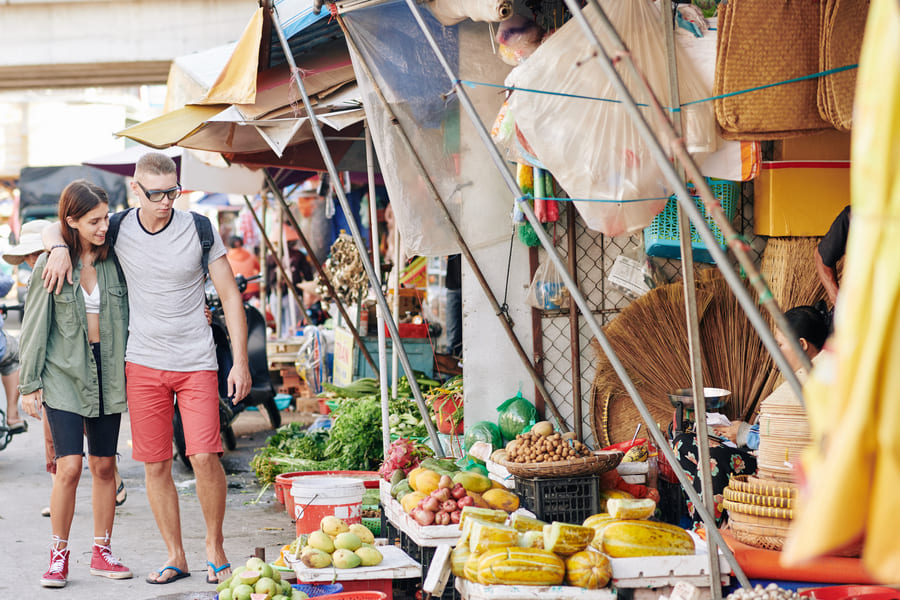 una pareja recorriendo un mercado chino con muchos productos naturales