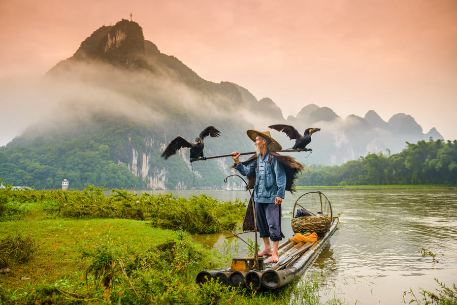 yangshuo con uncormoran en una pequena envarcacion en el rio